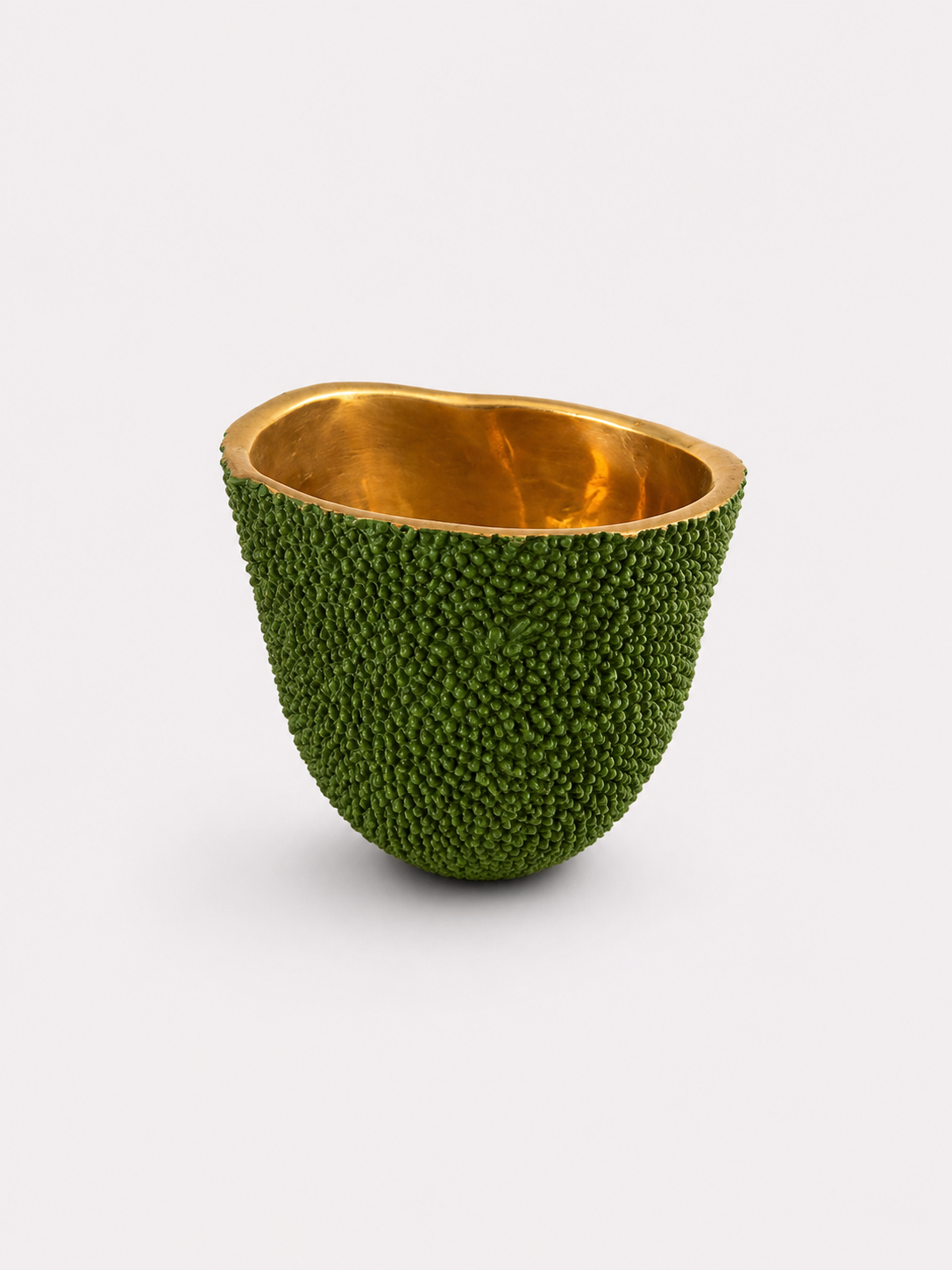 Decorative candle bowl made from a brass green fruit with gold interior on a white background
