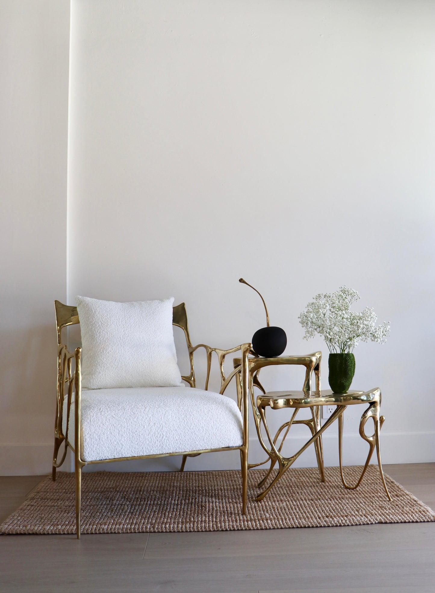 Gold armchair with white cushion and matching side table against a plain wall. Luxury handmade furniture