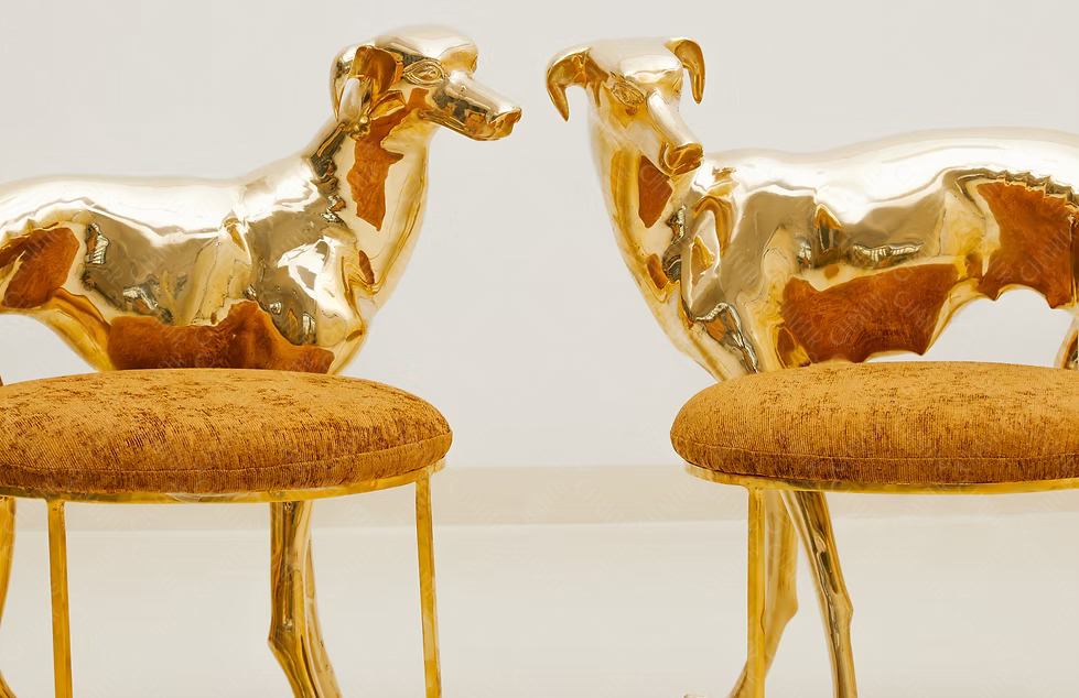 Two gold brass luxury handmade furniture dog-shaped chairs with cushioned seats, ideal for modern luxury decor, on a white background.