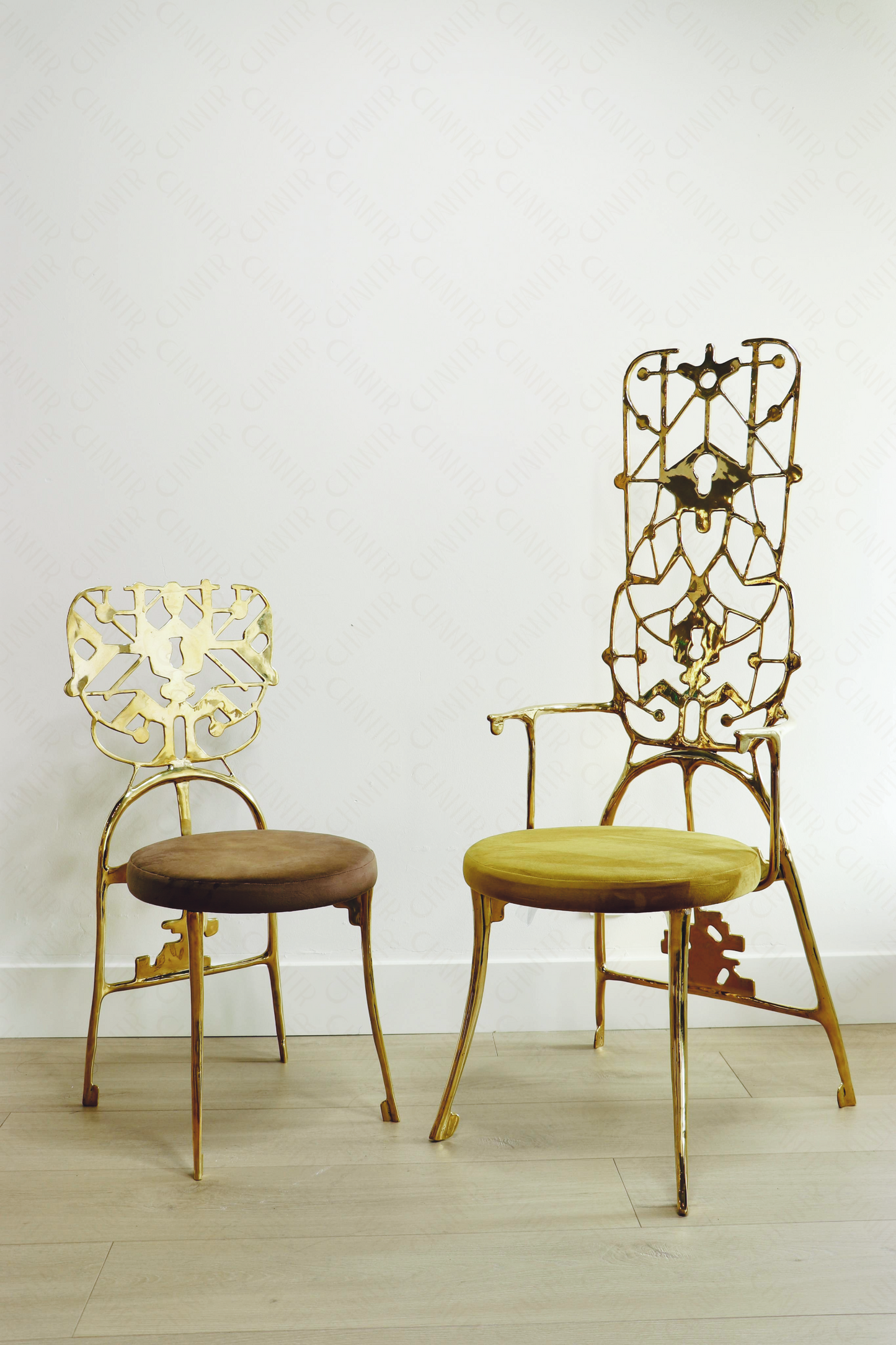 Two gold brass luxury handmade furniture chairs with intricate designs, ideal for modern luxury decor, on a white background.