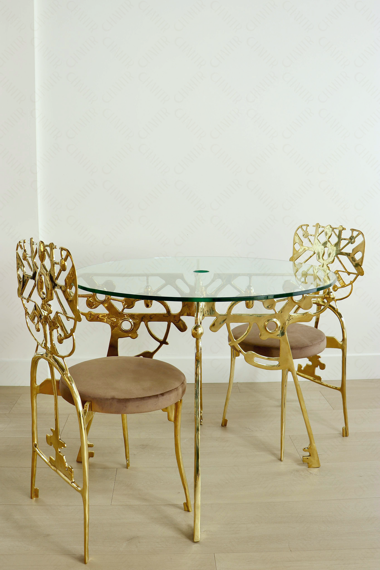 Gold dining set with glass table and chairs on a light wooden floor. Luxury handmade furniture