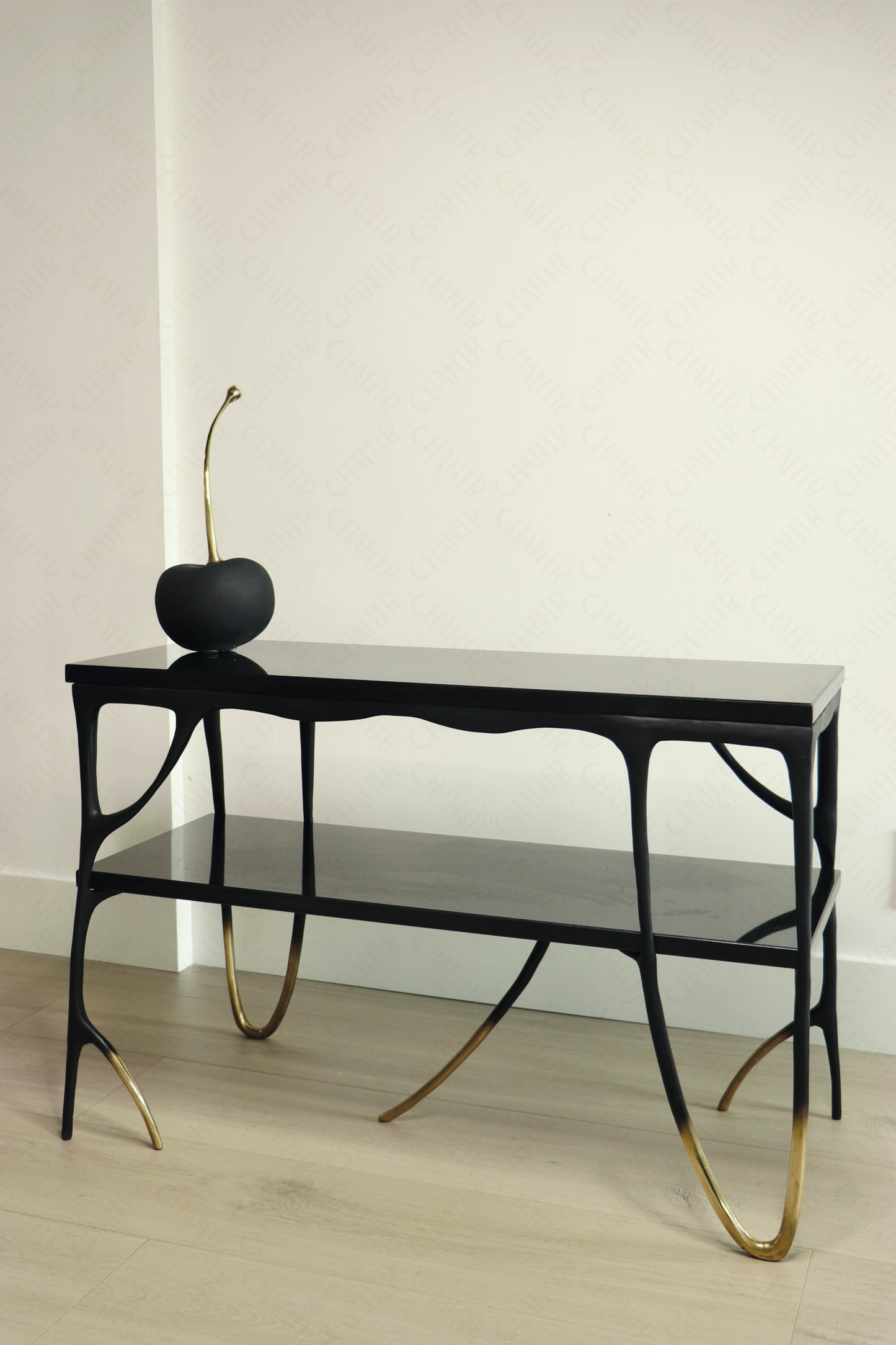 Modern black brass luxury handmade furniture console table with gold tips and black marble accents, perfect for modern luxury decor, on a plain background. with a brass cherry on top.