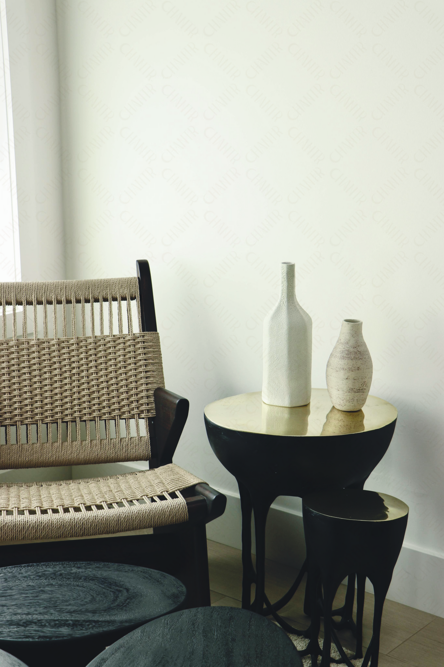 Modern interior featuring a luxury handmade furniture chair and black brass side table with vases, perfect for modern luxury decor, against a white wall.