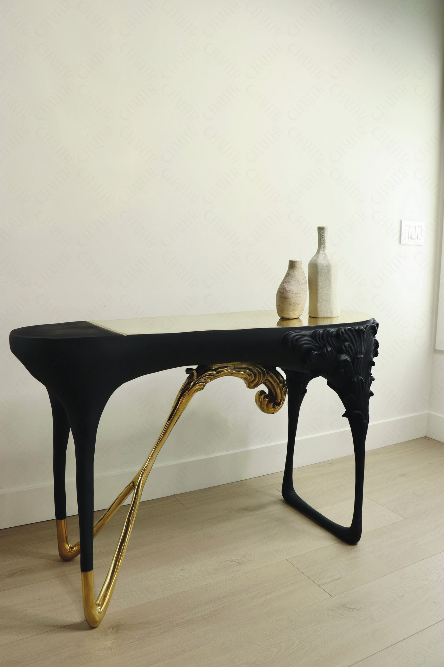 Black console table with gold brass accents, luxury handmade furniture, styled with two vases, perfect for modern luxury decor, against a white wall.