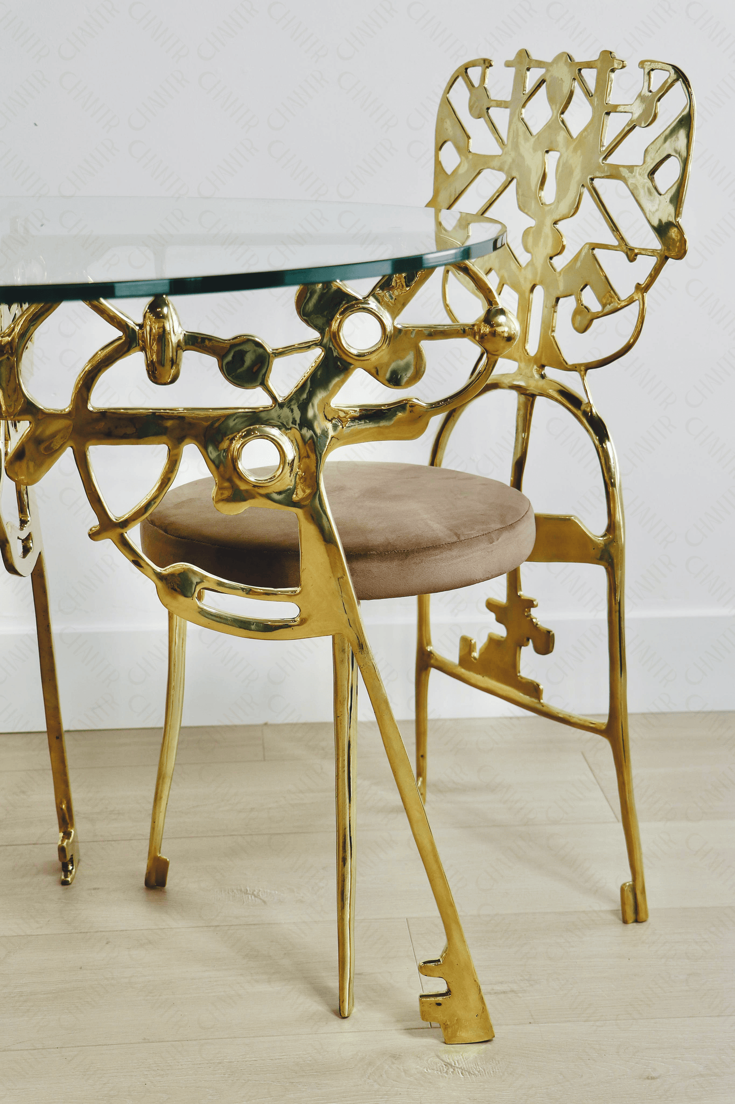 Gold brass luxury handmade furniture dining table and chairs with glass top, perfect for modern luxury decor, on a light wooden floor.