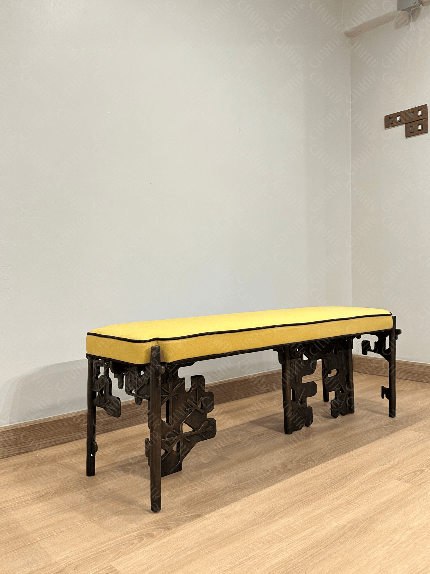 Brass luxury handmade furniture bench with yellow cushioned seat, ideal for modern luxury decor, against a white wall. Side angle