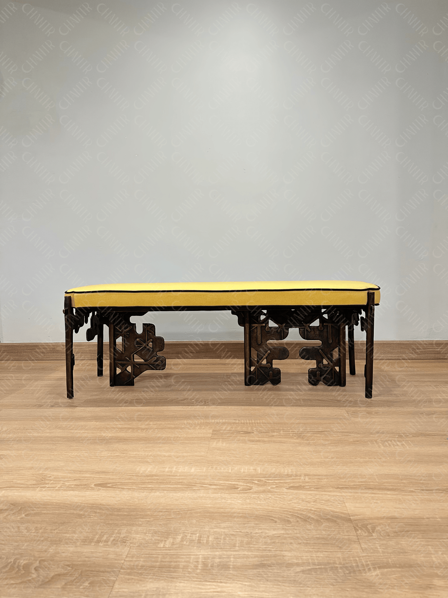 Brass luxury handmade furniture bench with yellow cushioned seat, ideal for modern luxury decor, against a white wall. Straight angle