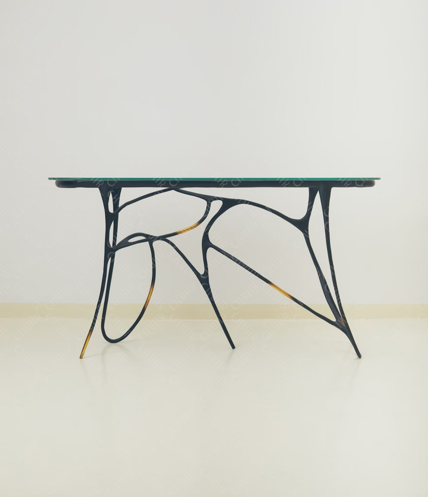 Black brass luxury handmade furniture table with organic design and glass top, perfect for modern luxury decor, on a light wooden floor with white wall background.