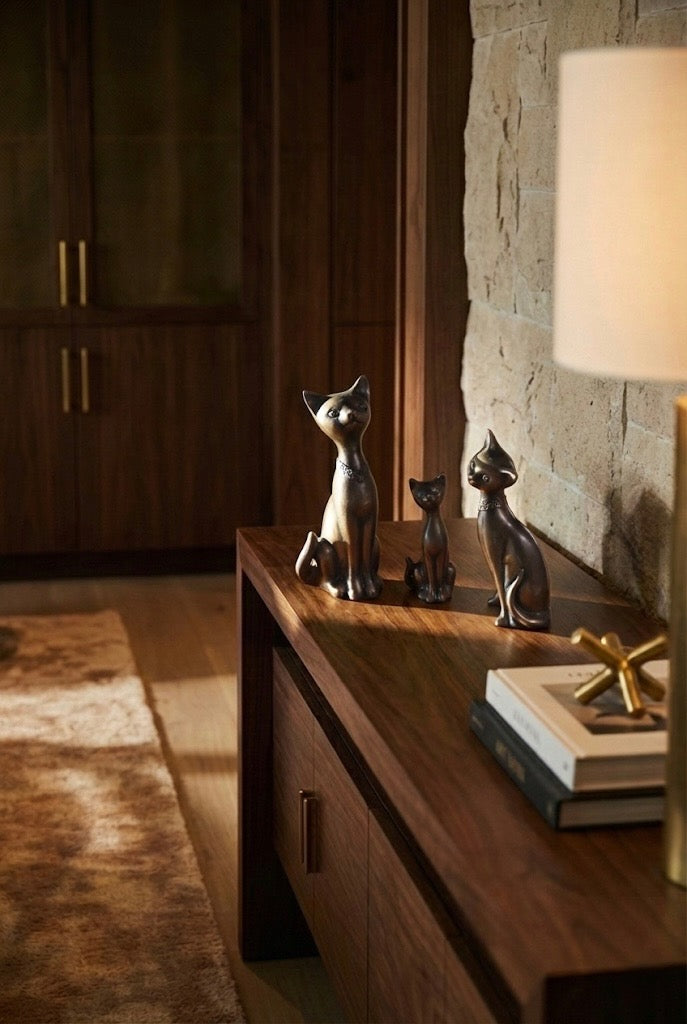 Three bronze cats on a wooden console.