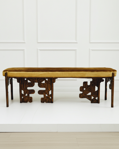 Luxury handmade brass bench with yellow mustard velvet cushion against a white paneled wall