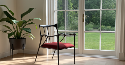 luxury handmade brass Chair with red cushion in a room with large windows showing greenery outside