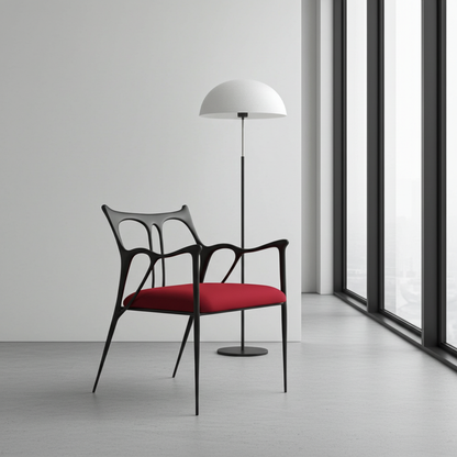 Modern brass chair with red cushion and black frame in a minimalistic room with a floor lamp and large windows.