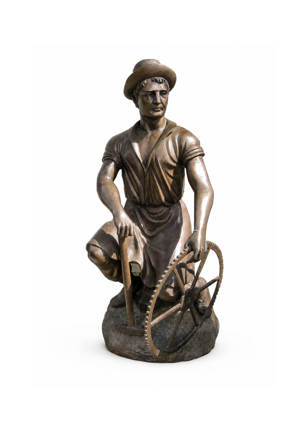 A bronze sculpture of a worker kneeling beside a large gear wheel, holding a tool in one hand, photographed on a plain white background.