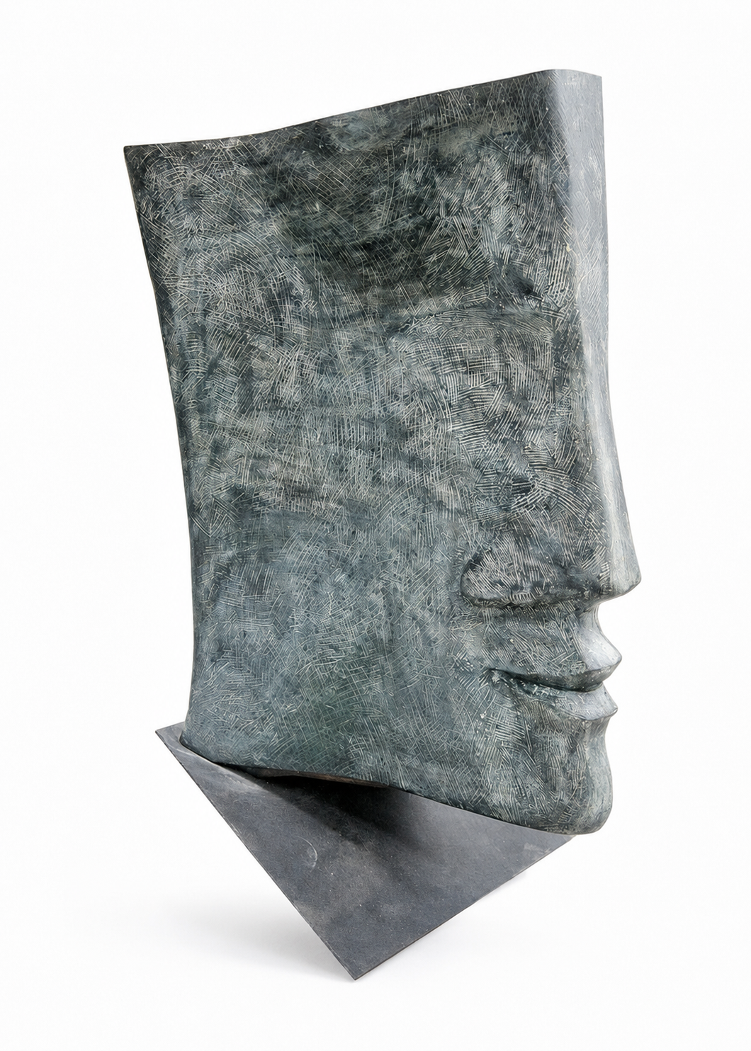 A bronze textured, sculptural book-shaped object with a metallic finish in muted blue-gray tones, displayed on a dark rectangular base against a clean white background.