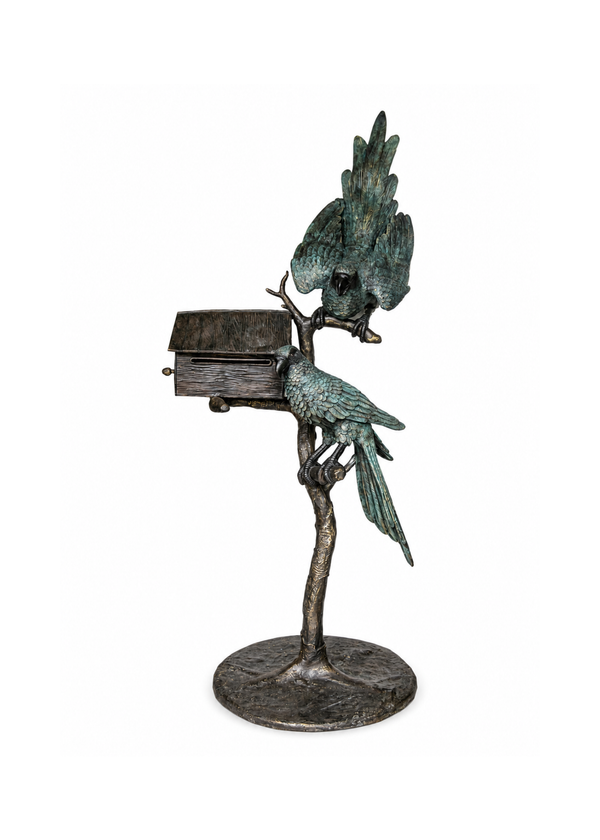 A bronze sculpture of two birds perched on a tree trunk with a small birdhouse attached, set against a plain white background.