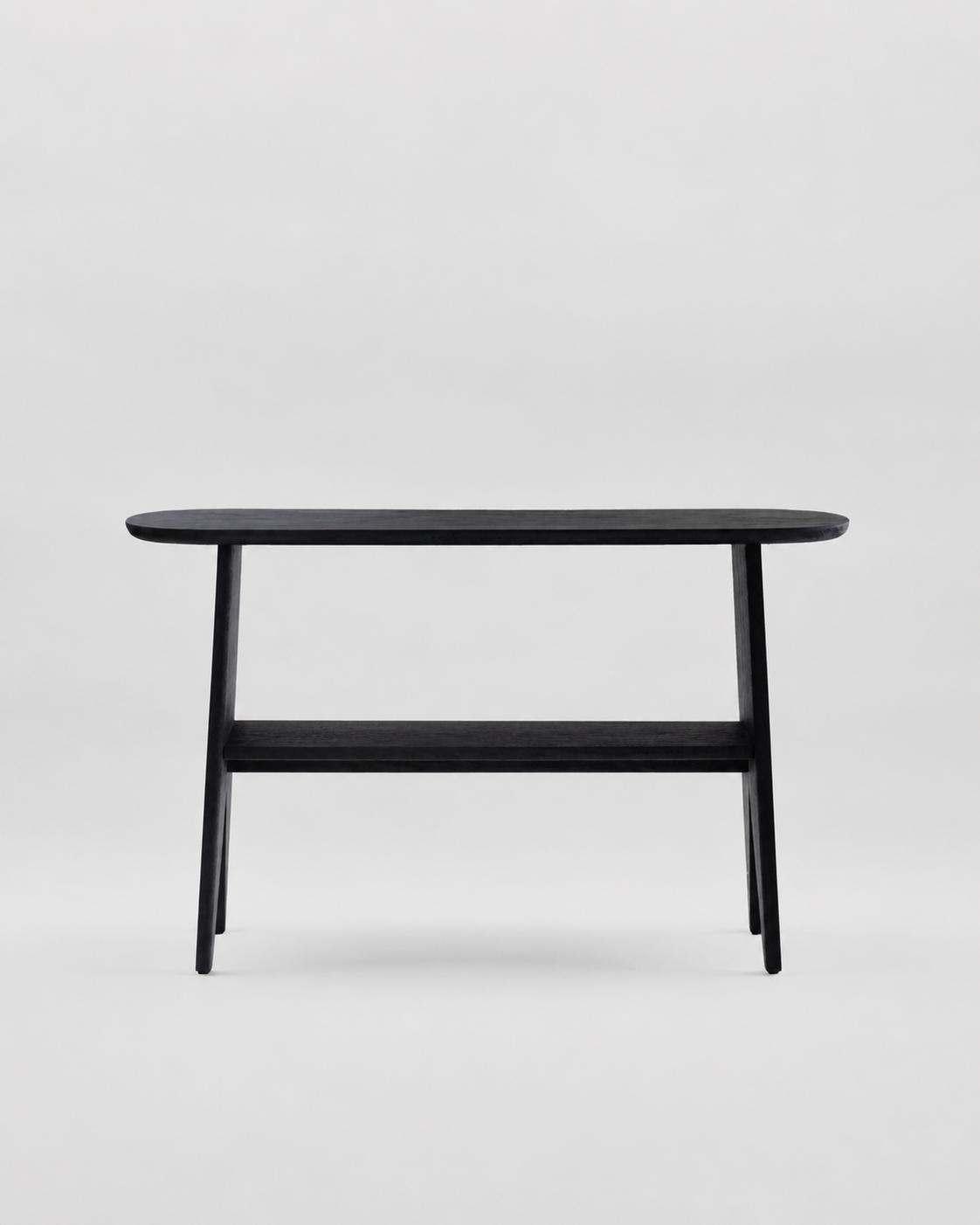 A minimalist black wooden console table with a rounded rectangular top, tapered legs, and a lower shelf, shown against a light gray studio background.
