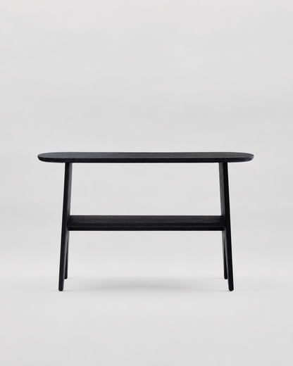 A minimalist black wooden console table with a rounded rectangular top, tapered legs, and a lower shelf, shown against a light gray studio background.
