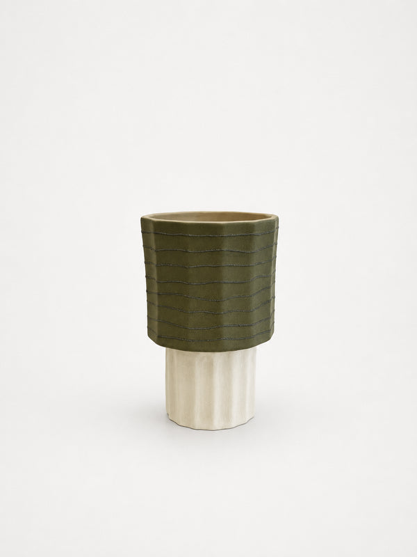 Green ceramic vase with ribbed texture on a white background