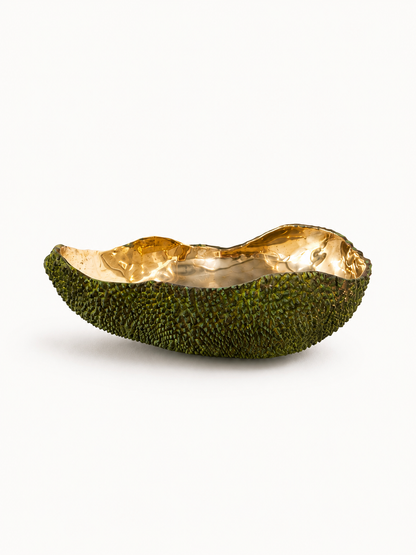 Decorative bowl made from a brass green fruit with gold interior on a white background