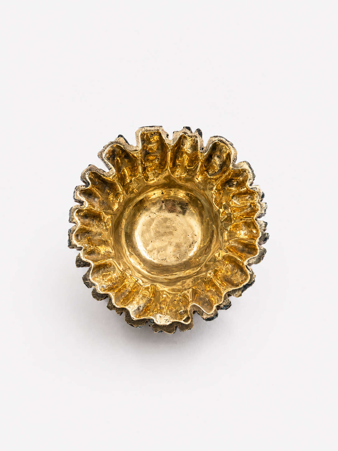 Gold decorative object with a sunburst design on a white background