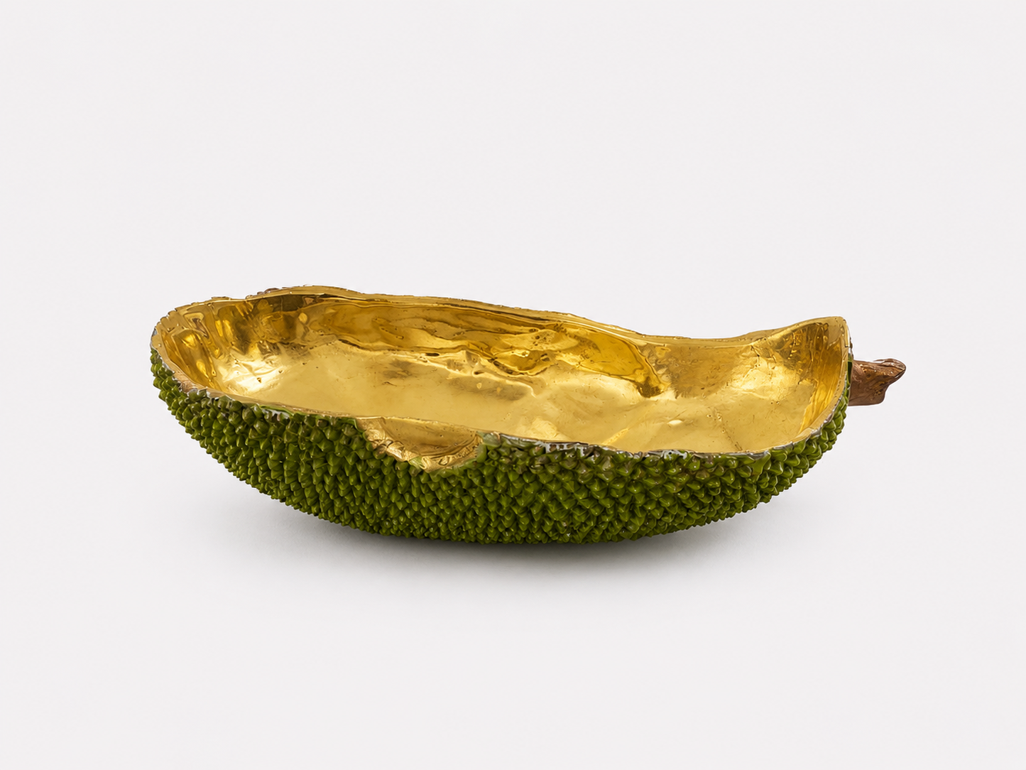 Decorative bowl made from a brass green fruit with gold interior on a white background