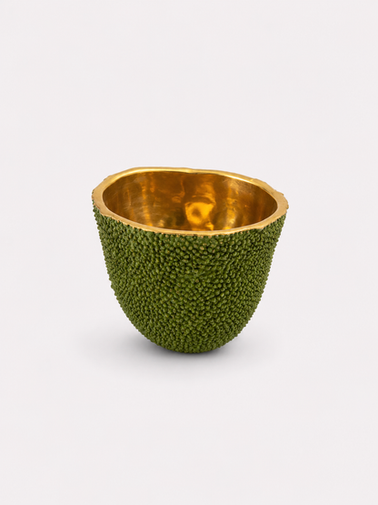 Decorative candle bowl made from a brass green fruit with gold interior on a white background