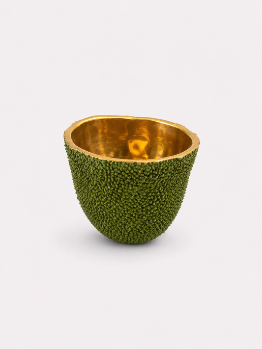Decorative candle bowl made from a brass green fruit with gold interior on a white background