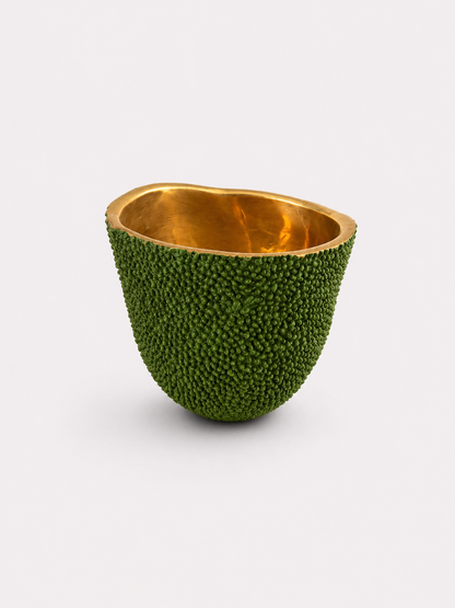 Decorative candle bowl made from a brass green fruit with gold interior on a white background