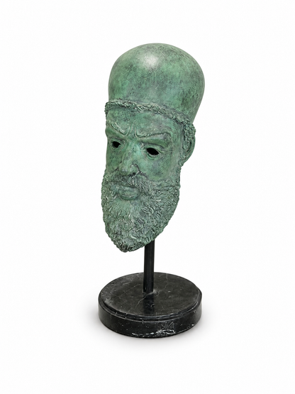 Green bronze mask on a stand and marble bottom against a white background. Side view. 