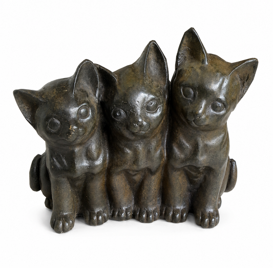 Bronze sculpture of three sitting kittens on a white background