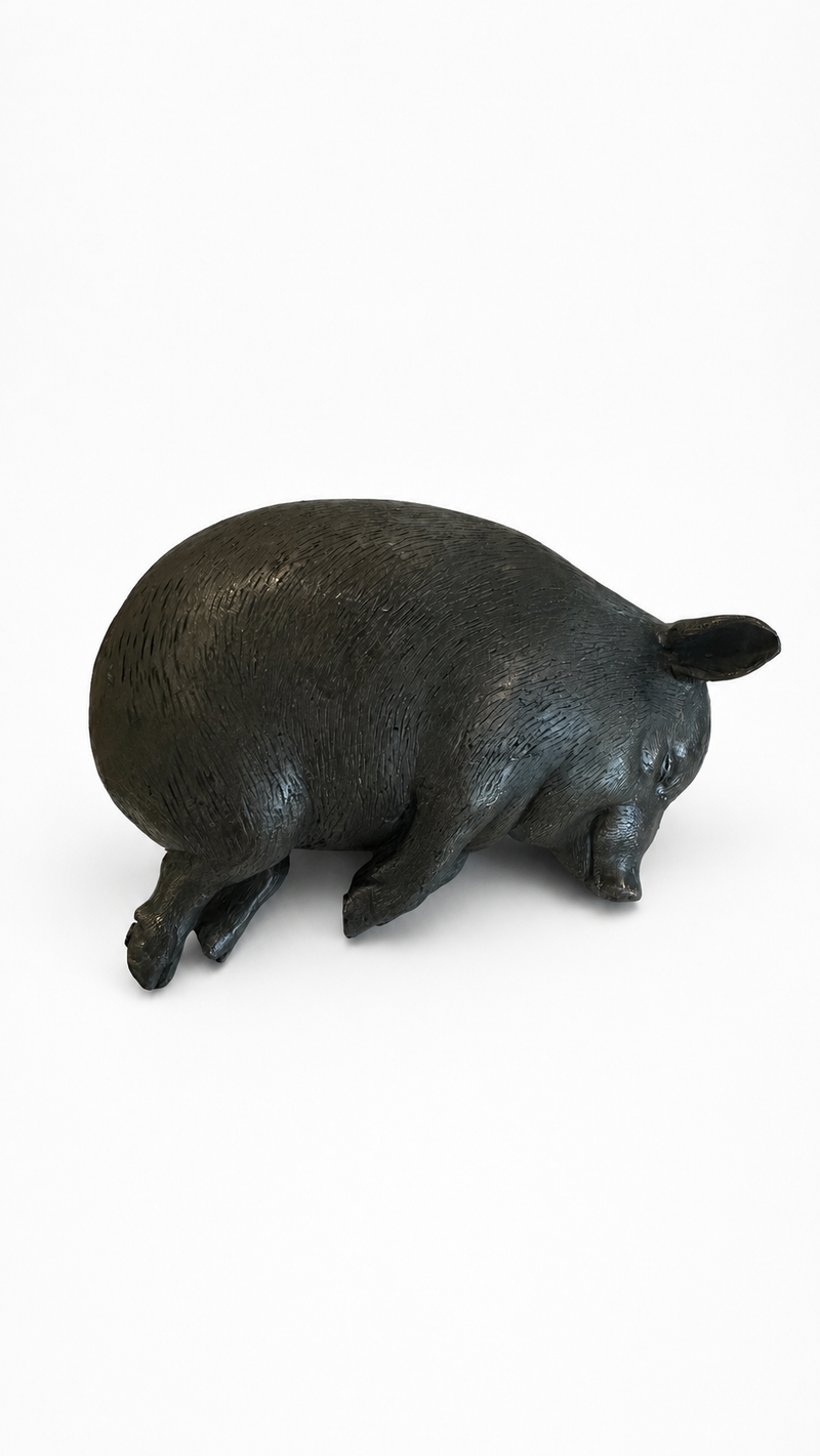 Bronze sculpture of a sleepy pig on a white background