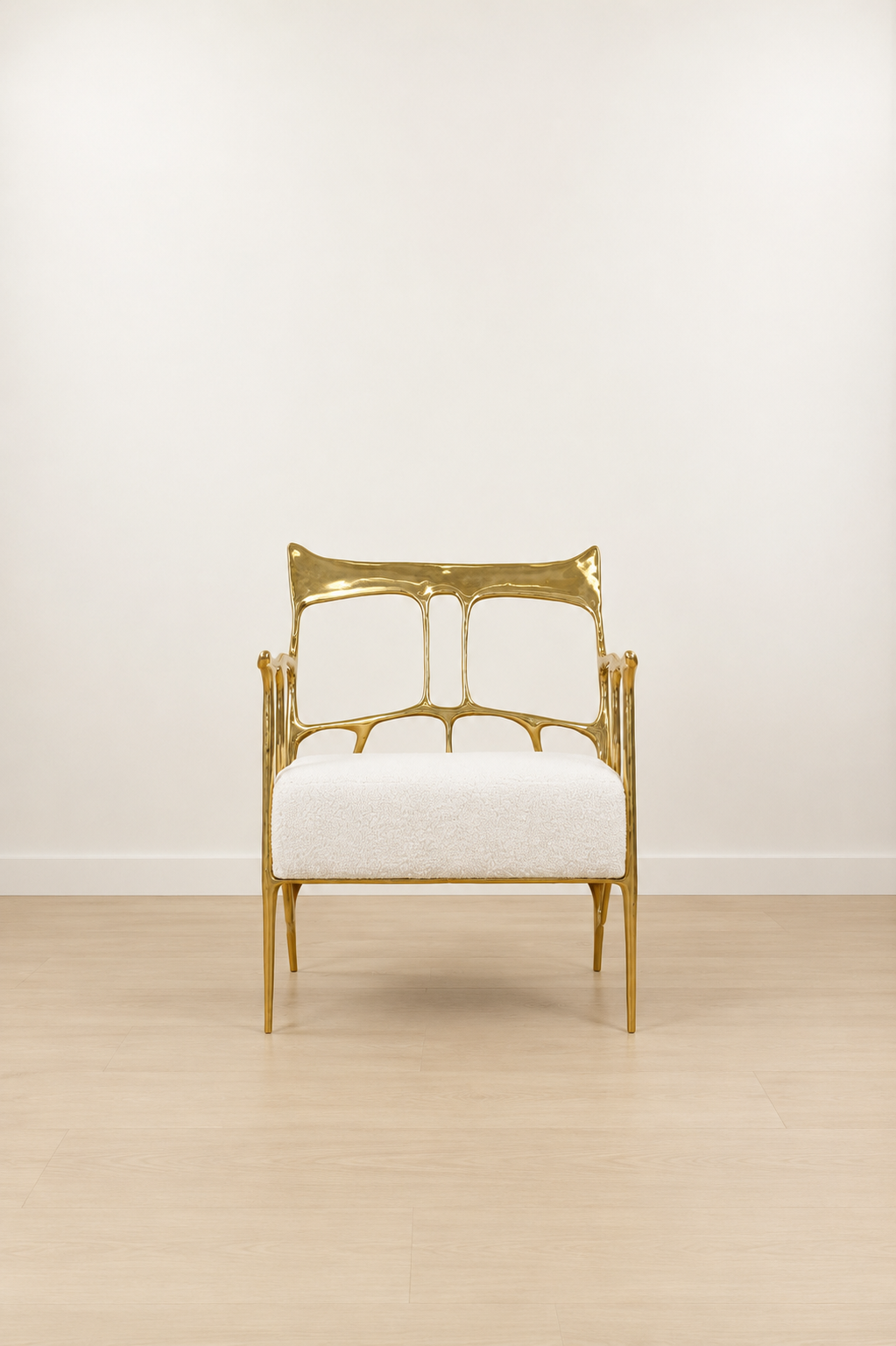 polished gold brass armchair with white cushion on a light wooden floor and white wall background. straight view