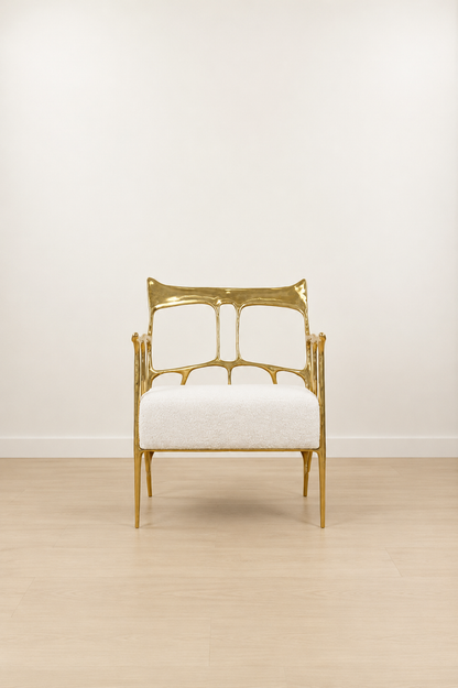 polished gold brass armchair with white cushion on a light wooden floor and white wall background. straight view
