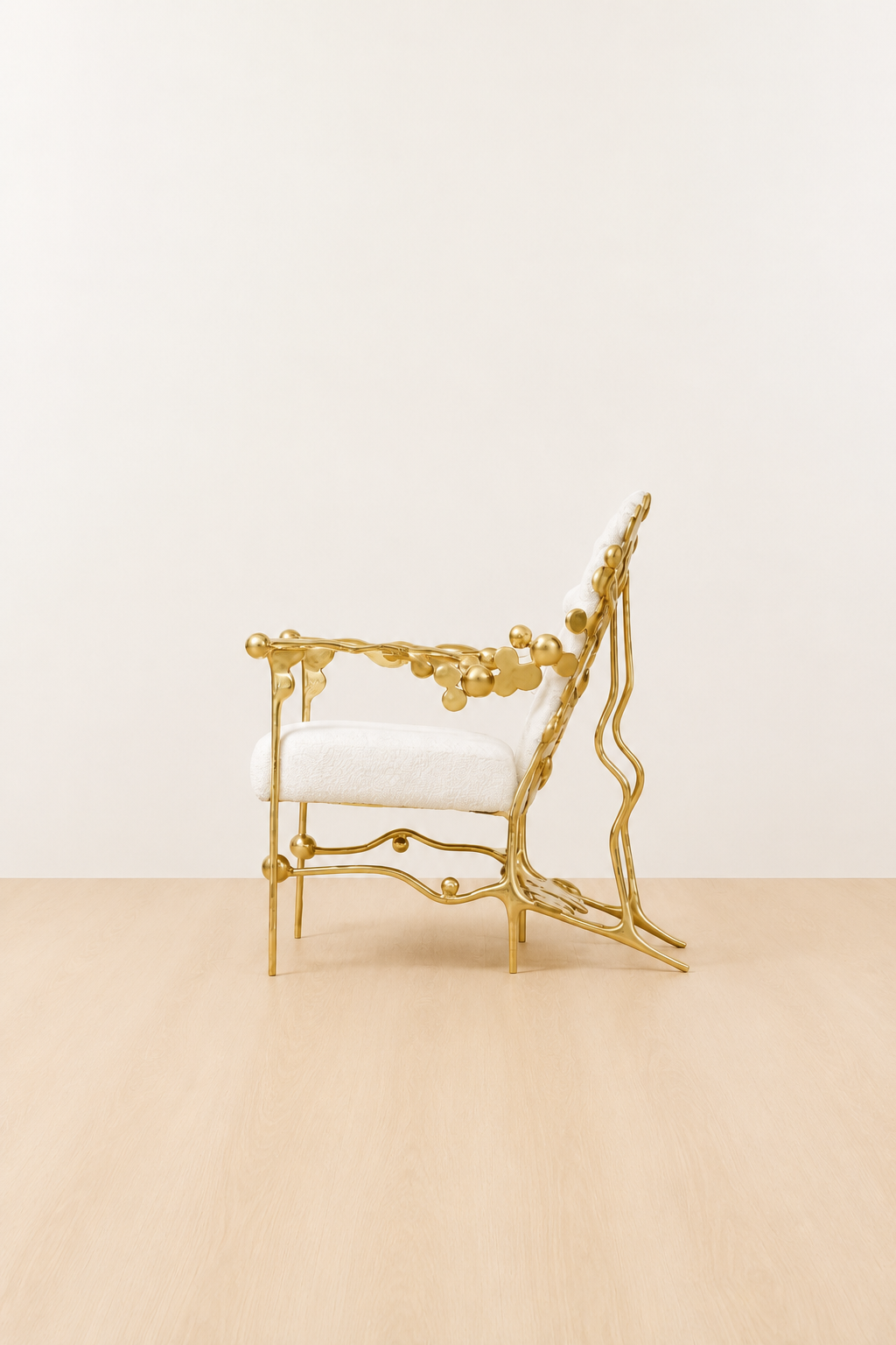 gold brass polished chair with white cushion on a beige floor and light beige wall. side view