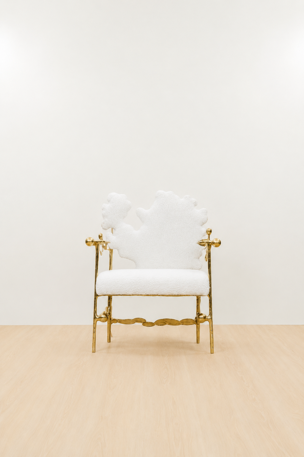 gold brass polished chair with white cushion on a beige floor and light beige wall. straight view.