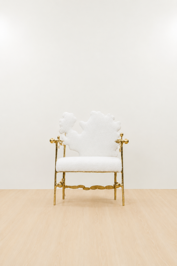 gold brass polished chair with white cushion on a beige floor and light beige wall. straight view.