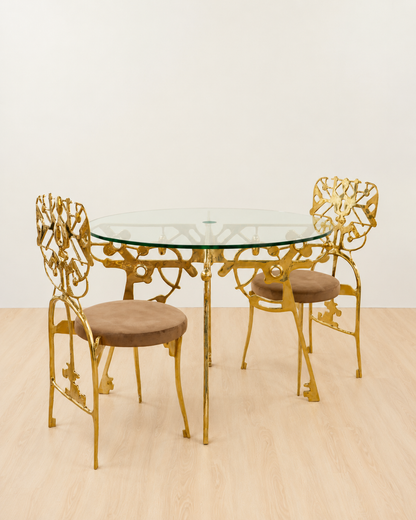 Gold brass dining set with a glass table top on gold brass base.  