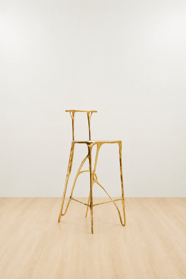 Gold brass bar stool on a white and beige background