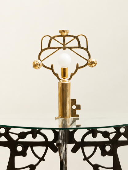 Decorative table with intricate metalwork and a glass top on a light background