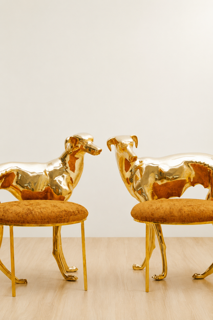 Two gold brass luxury handmade furniture dog-shaped chairs with orange cushioned seats, ideal for modern luxury decor, on a white background.