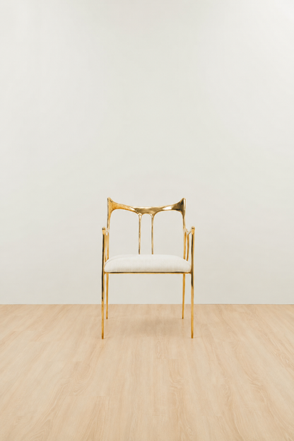 Luxury handmade brass chair with white cushion and gold finish on a plain background