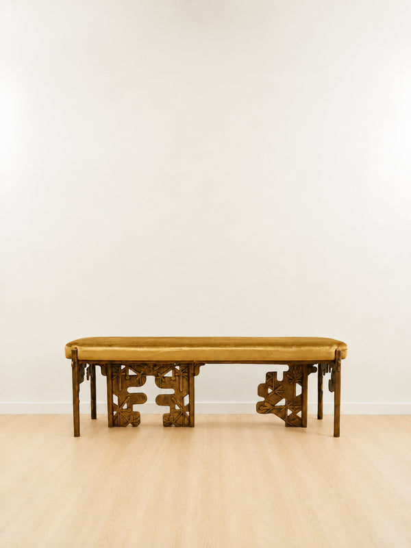 brass bench with intricate carvings with a yellow velvet cushion on a plain background. portrait mode. 