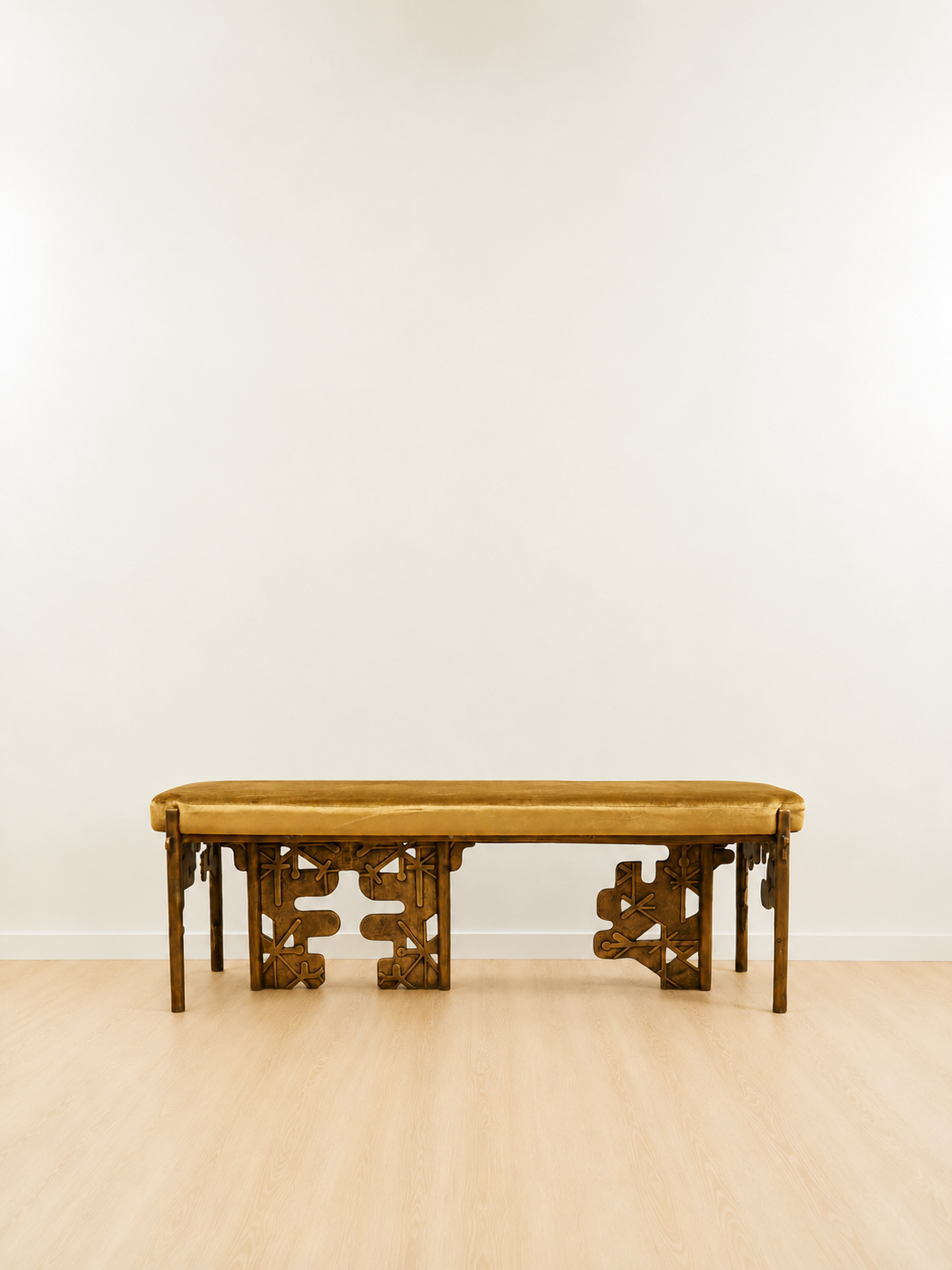 brass bench with intricate carvings with a yellow velvet cushion on a plain background. portrait mode. 