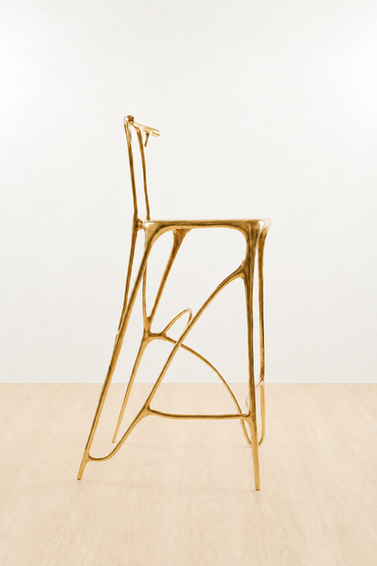 Gold brass bar stool on a white and beige background. side view