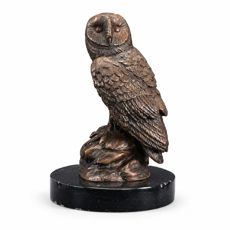 Bronze owl statue on a black marble base against a white background