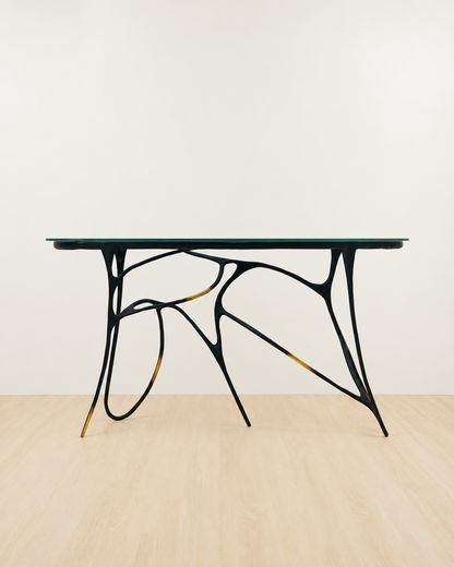 Modern brass console  table with black metal legs and glass top on a beige floor and white wall background