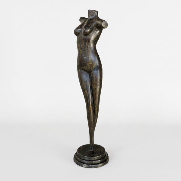 A dark bronze sculpture of a stylized female torso and legs standing on a round base, photographed against a plain light gray studio background.