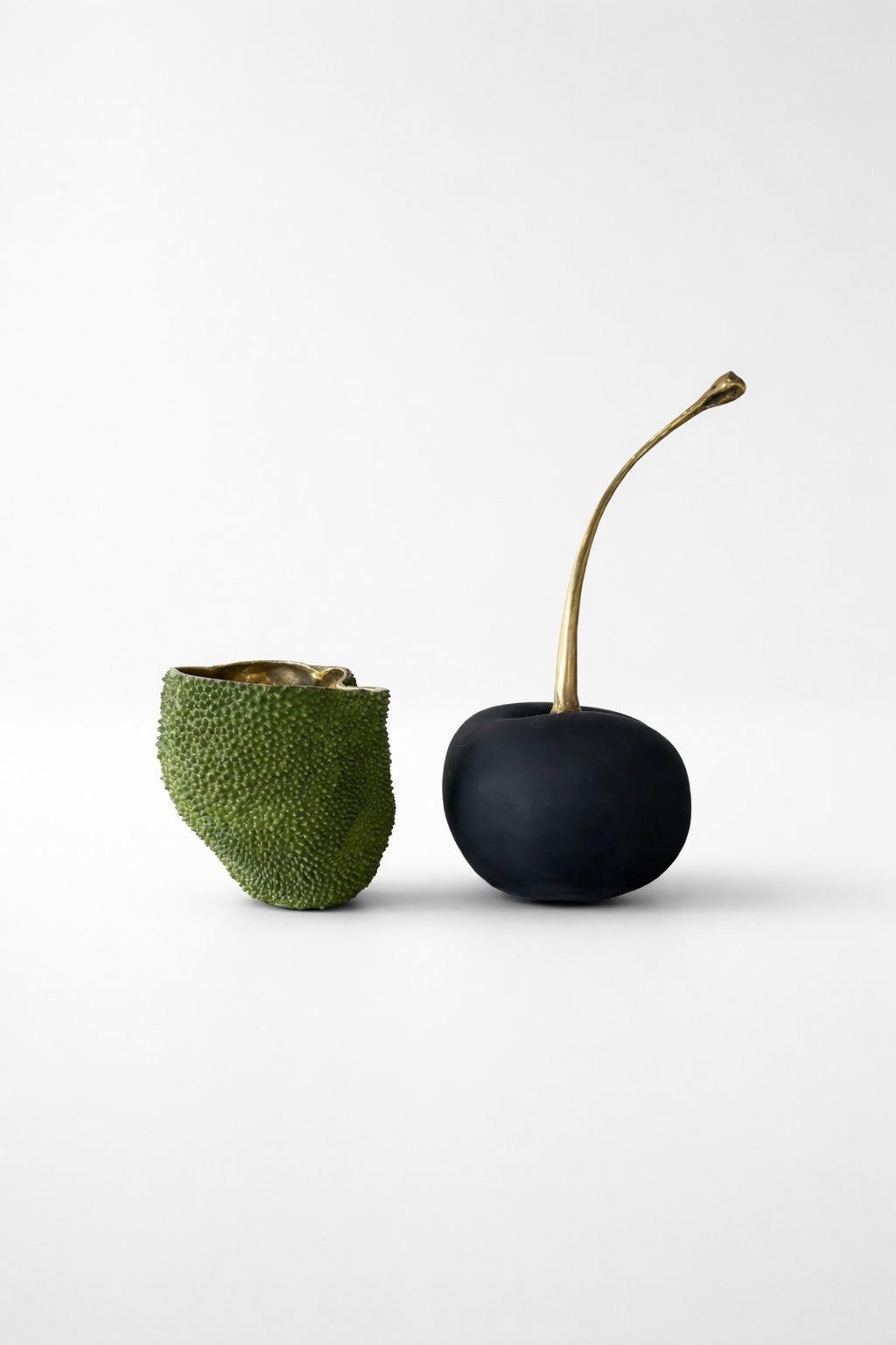 Black brass cherry with a textured green brass decor on a white background