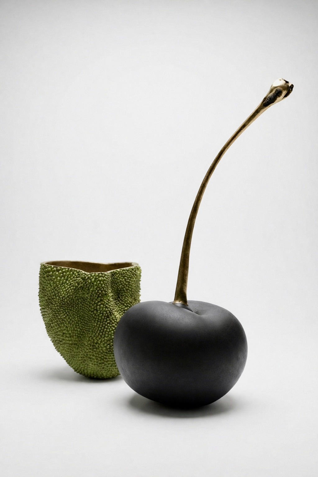 Black brass cherry with a textured green brass decor on a white background