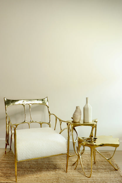 Gold brass luxury handmade furniture chair with two gold brass side tables, styled with vases, perfect for modern luxury decor, on a beige background.